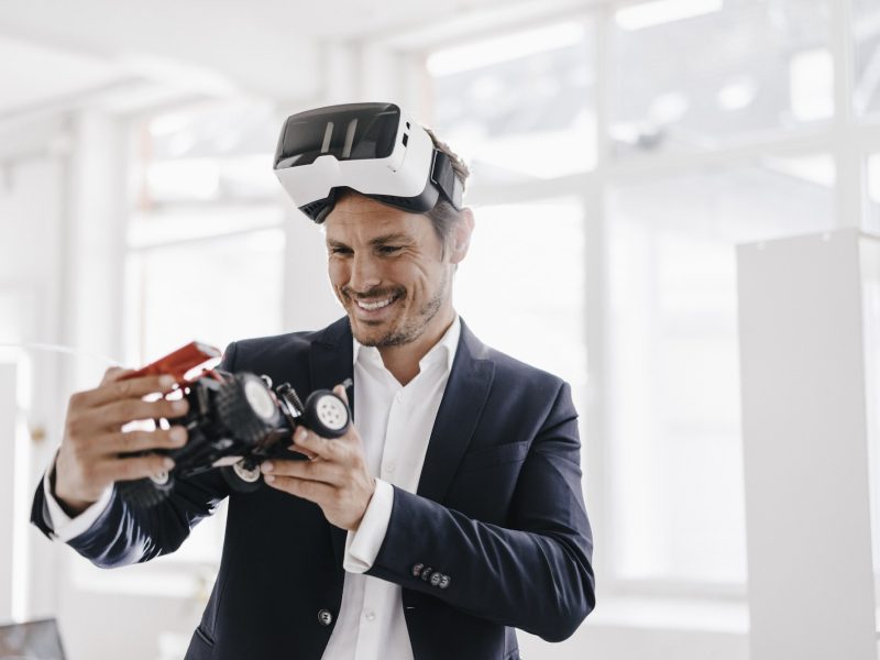 smiling-businessman-wearing-vr-glasses-looking-at-toy-racing-car.jpg
